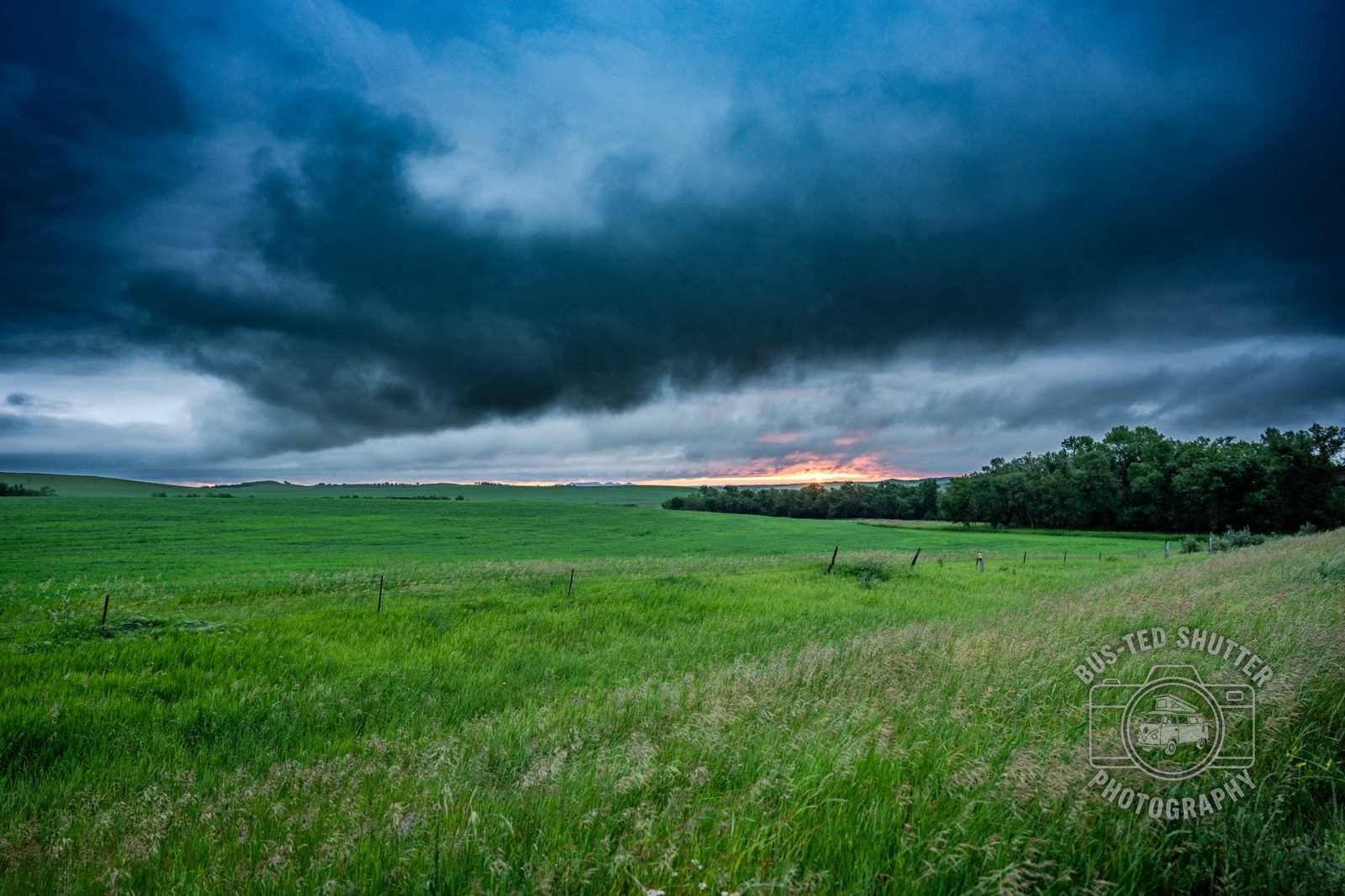Storm clouds breaking over a green prairie at sunset